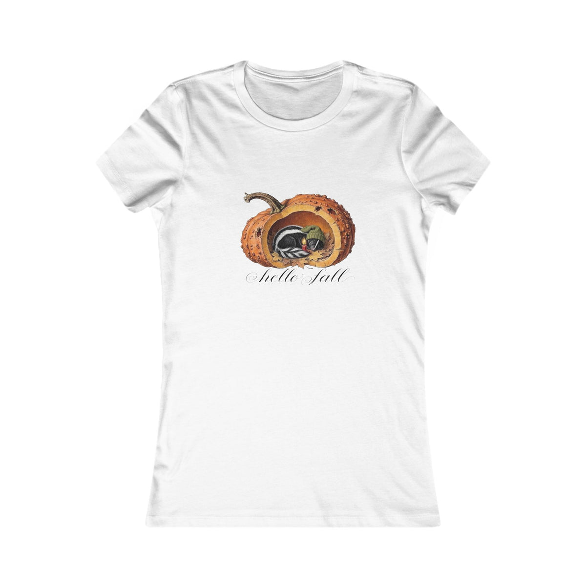 A white short-sleeve crewneck t-shirt featuring a graphic of a fall pumkin cutaway with a cute little skunk in a stocking cap napping inside to the warmth of a candle  and the text 'Hello Fall' below it very cozy autumn vibes victorian bookplate style